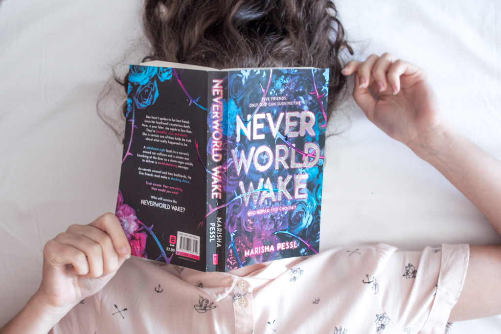 Overhead shoot of a woman laying down with her hair going upwards and the book "Neverworld Wake"covering her face.