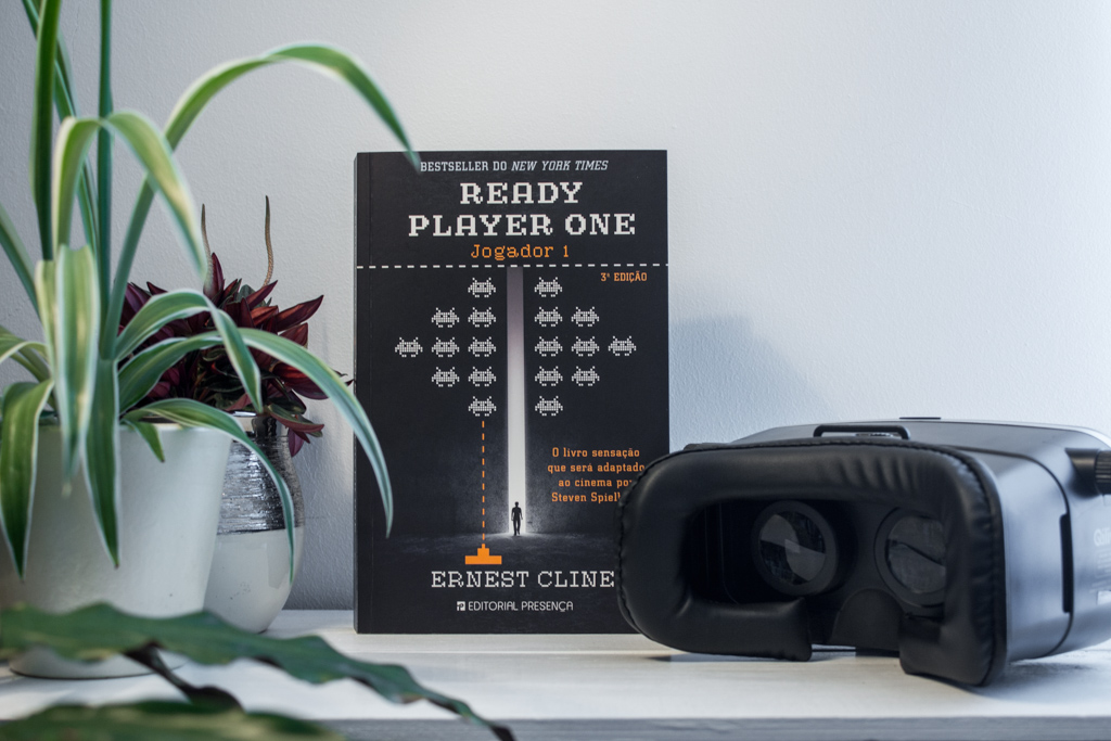 Photo of the book Ready Player One by Ernest CLine in the Portuguese edition standing up next to a pair of VR goggles.
