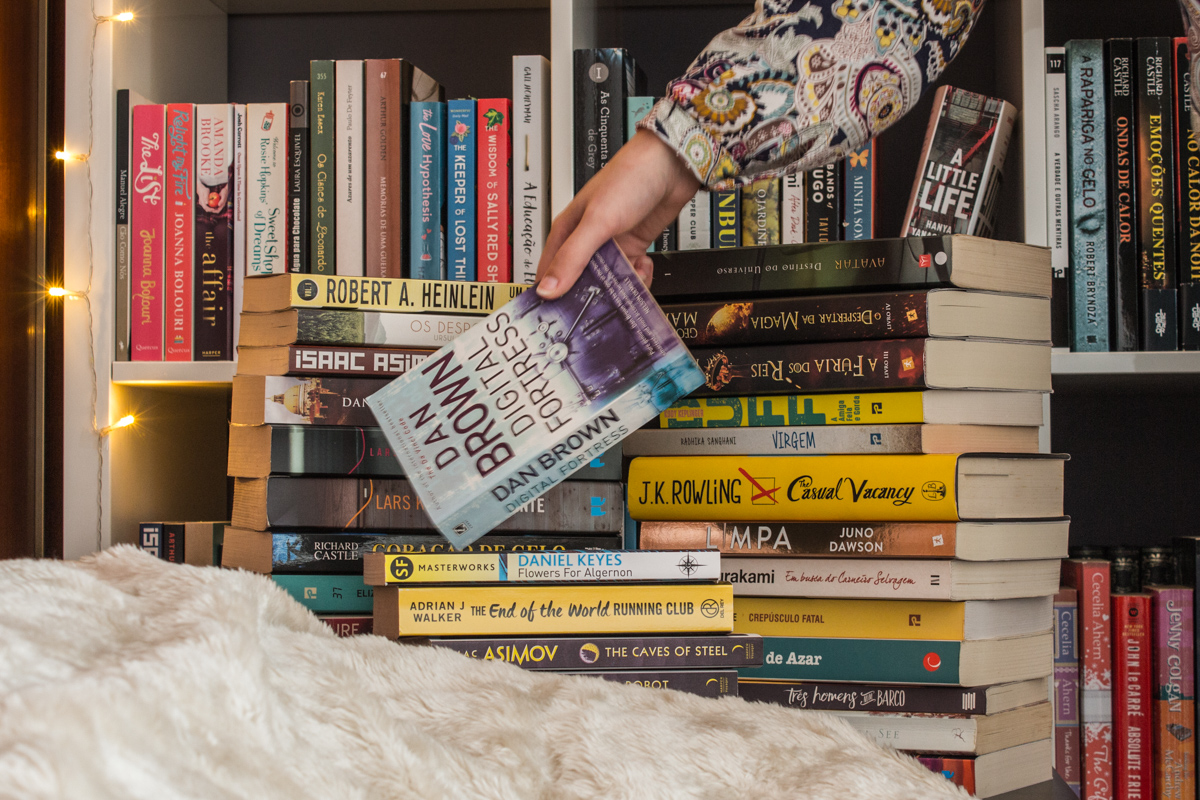 Picking up a book from various stacks of books.