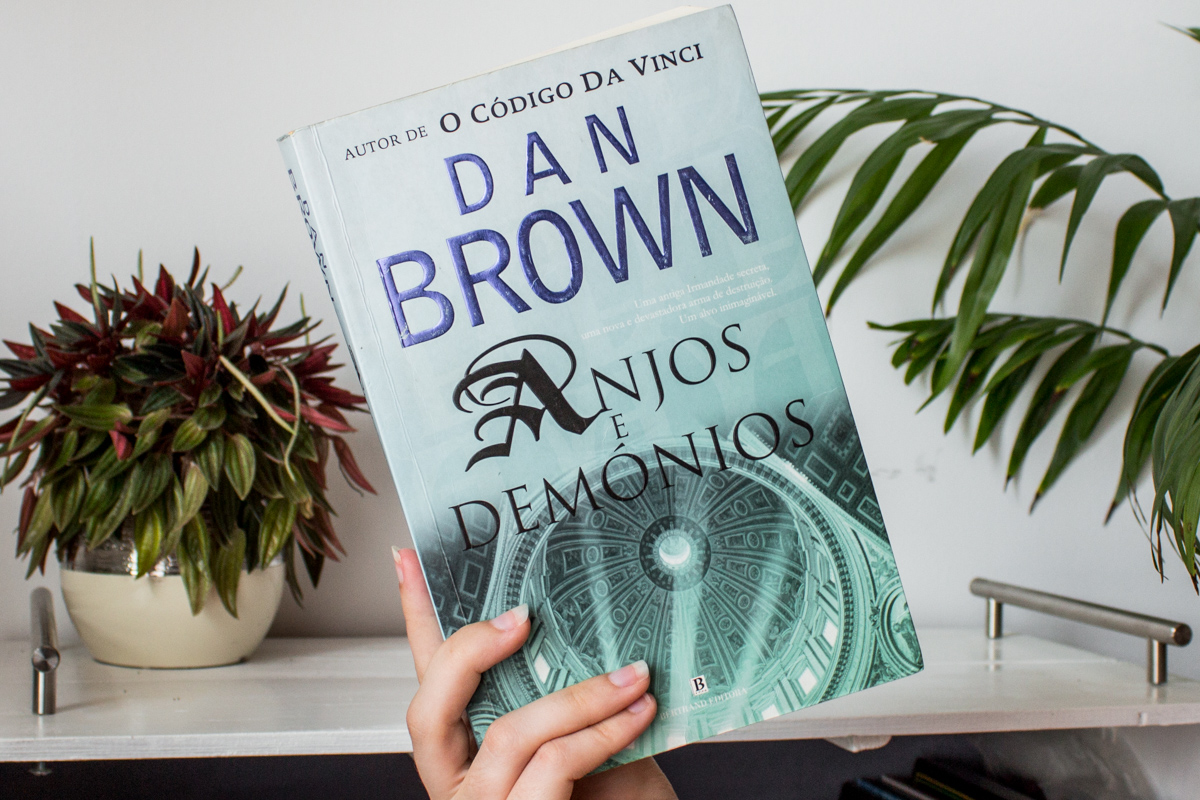 Holding the book Angels and Demons by Dan Brown.