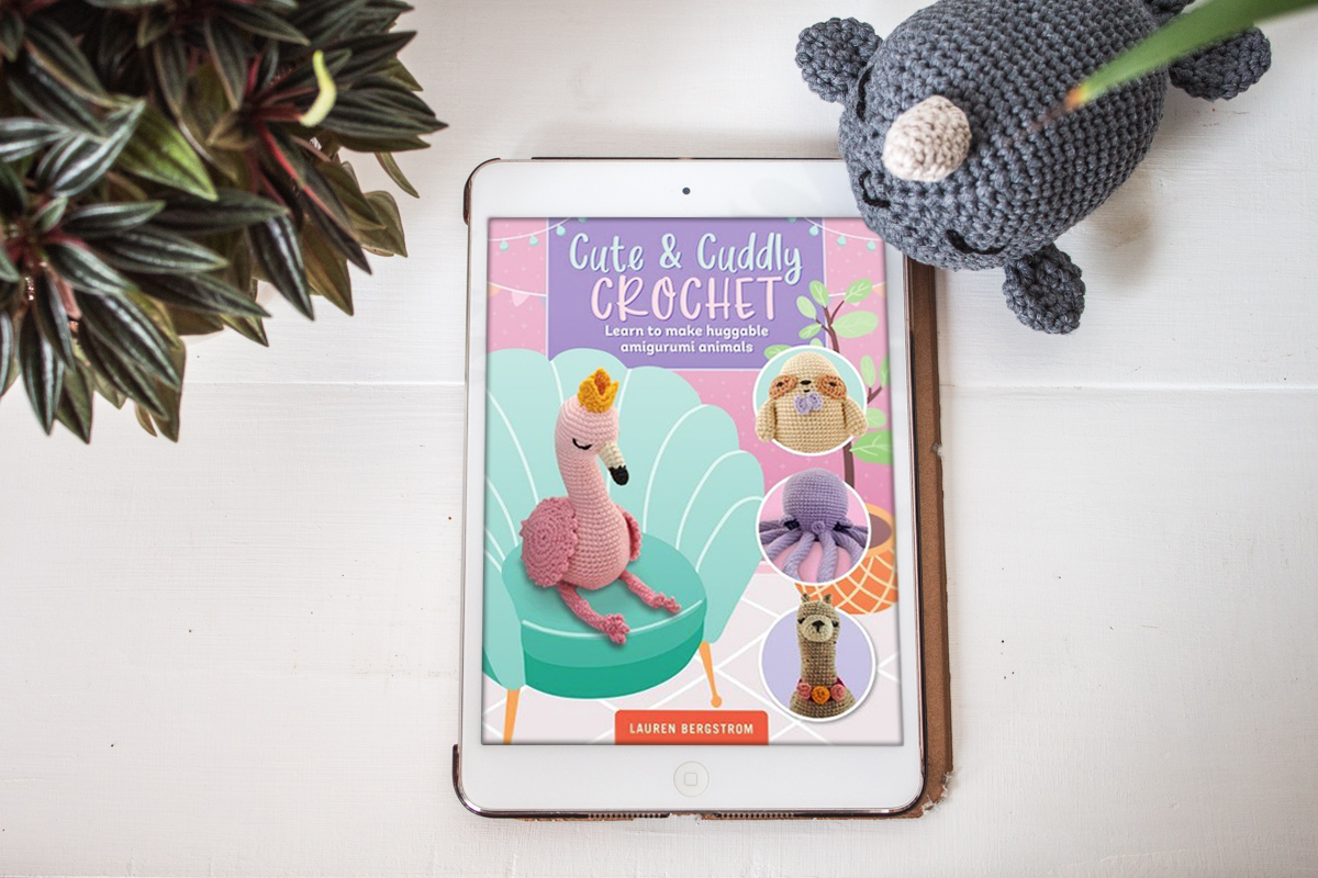 Book cover on an Ipad next to a crochet narwhal.