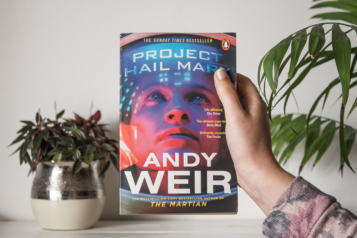 Holding with one hand the book Project Hail Mary.