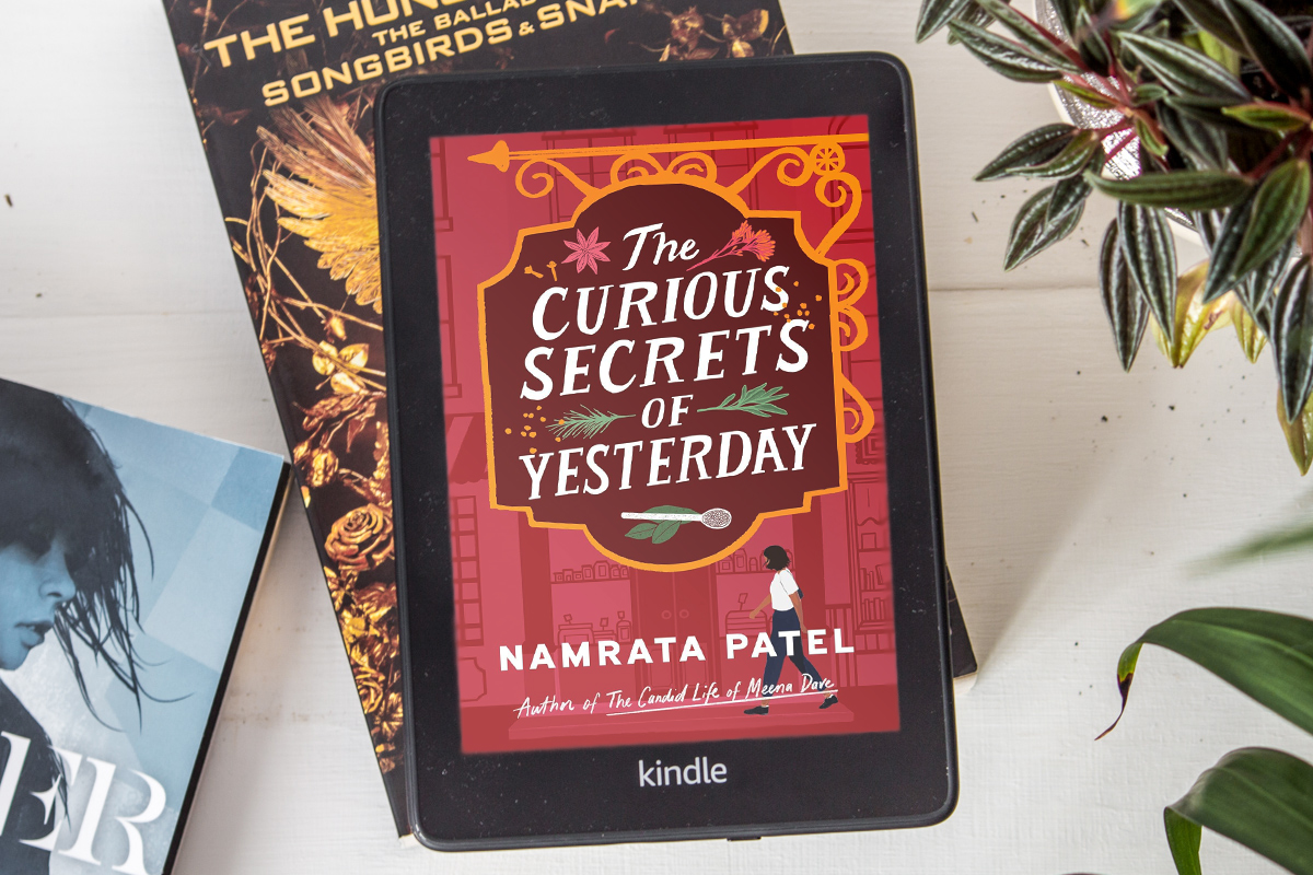 Ereader laying on books showing a colour version of The Curious Secrets of Yesterday.