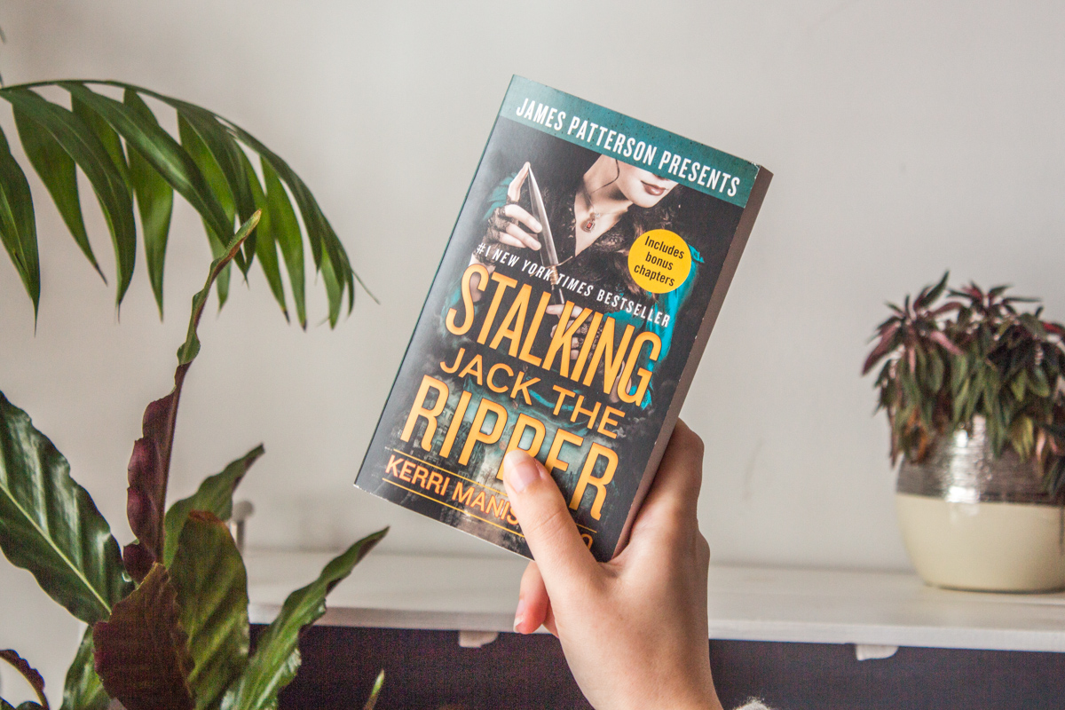 Holding the book up with one hand.