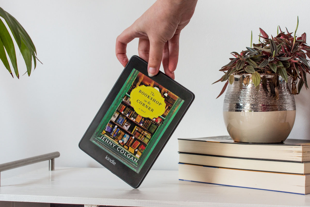Holding a Kindle with one hand showing the colour cover of the book.