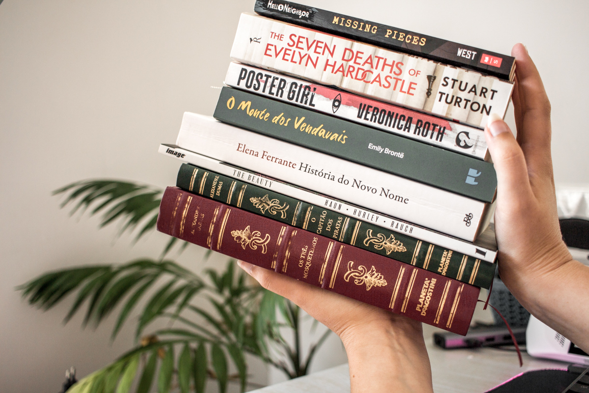 Holding a stack of the books read in the past four months.