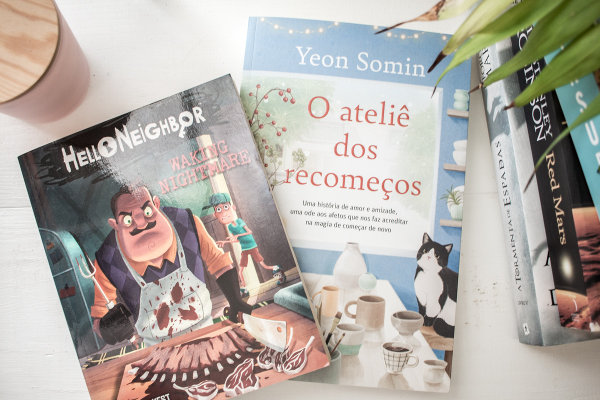 Cover of the books read in July for HRCYED 3 next to a pile of books.